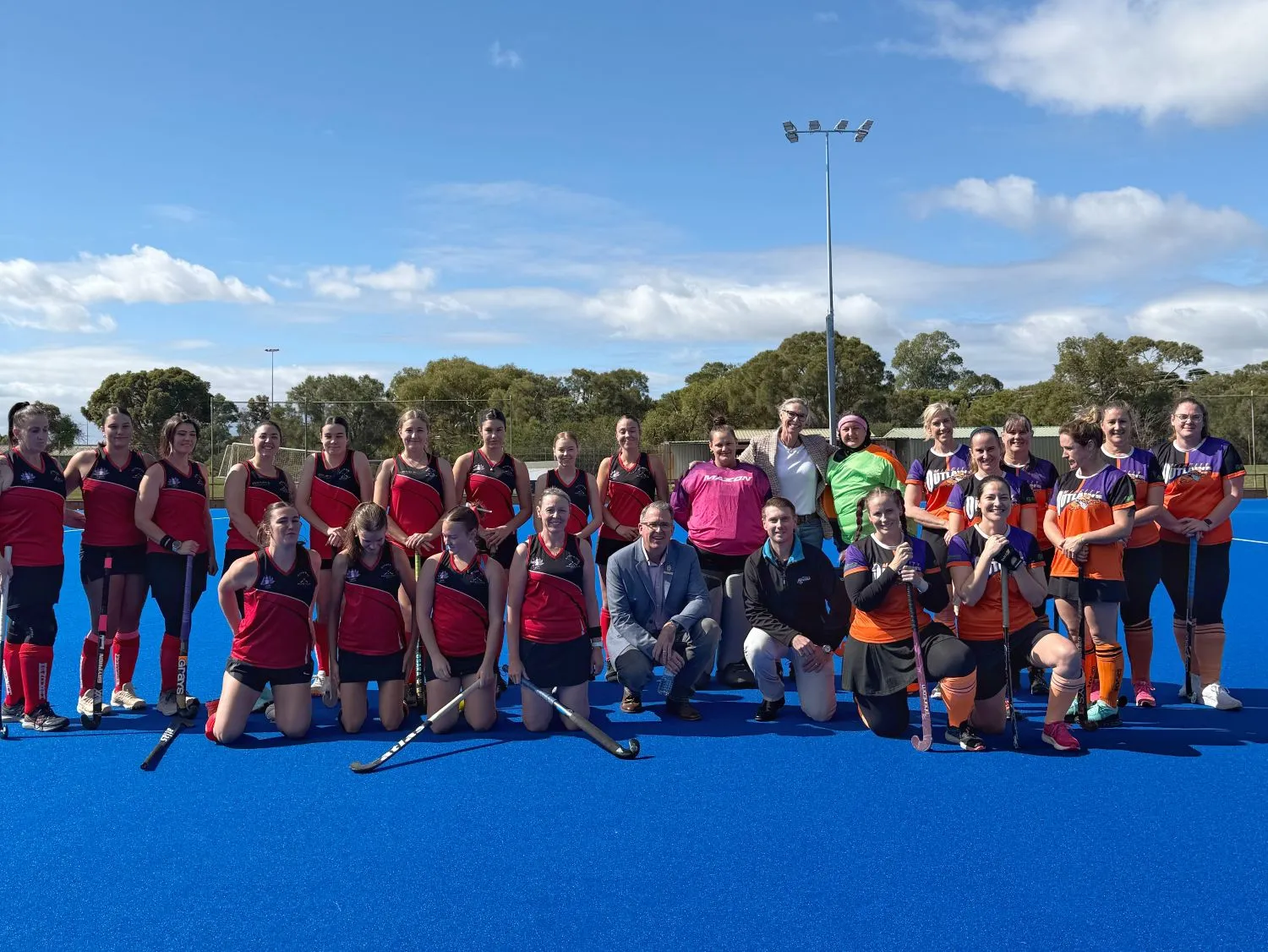Hockey players with council members standing on new hockey turf.